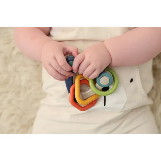 Bunte Rassel in Dreiecksform mit drei unterschiedlich geformten Anhängern.