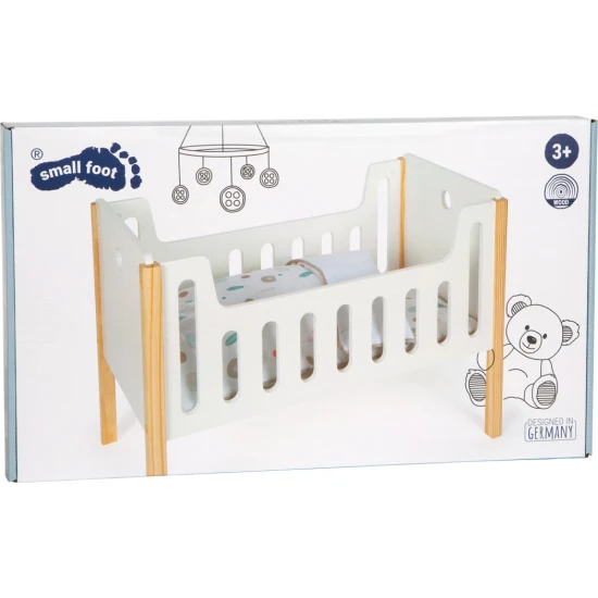 Weißes Puppenbett aus Holz mit Laken.