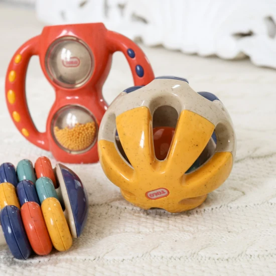 Bunte Rassel in Ballform mit Löchern zum einfachen Greifen in Babyhänden